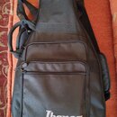 Černý poloměký pouzdro (gig bag) na hudební nástroj z textilního materiálu. Na přední kapse je bílý nápis Ibanez. Pouzdro má nosní úchyt, ramenní pop…