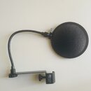 Černý popfilter s kulatou síťovkou z látky a ohybatým ramenem. Na upevňovacím držáku je bílý nápis "Rhythm Dynamics" a pod ním označení modelu "PDS-M…
