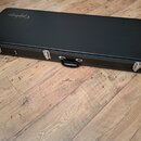 Černý obdélníkový kufřík na hudební nástroj s nápisem Epiphone v horním levém rohu. Kufřík má kovové zapínání a černou úchytnou rukojeť. Povrch je hl…