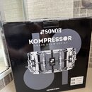 Černá papírová krabice s nápisy SONOR, KOMPRESSOR SNARE DRUM SERIES a webovou adresou sonor.com. Na krabici je zobrazen obrázek chromovaného malého b…