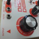 Detailní pohled na bílý efekt pedál s červenými prvky a nápisy. Na povrchu je uveden název dre.adbox DISORDER a označení ovládacích prvků SENSE, ENV…
