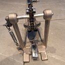 Fotografie znázorňuje basový pedál z kovového materiálu v šedé a chromované barvě. Pedál je vybaven řetězovým přenosem a pružinou s nastavitelností.…