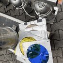 Fotografie zachycuje několik stříbrných reflektorů a sadu barevných gelů v kovových rámečcích. Gely mají kulatý výřez a jsou v barvách žluté, modré a…
