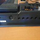 Záběr na zadní panel černého elektronického zařízení s nápisem Roland. Na štítku je uveden MODEL GR-20 a sériové číslo ZS66168, vedle nápisu MADE IN…