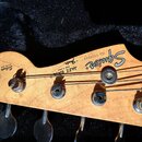 Detail hlavy basové kytary z jasného dřeva s viditnou masivním kresbou. Na povrchu jsou nápisy Squier, by Fender, MADE IN JAPAN a JAZZ BASS s číslem…