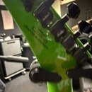 Záběr na zadní stranu zeleného krku elektrické kytary s černými ladicími kolíky. Na povrchu je černý nápis IGJ1505155 a pod ním text CRAFTED IN INDON…
