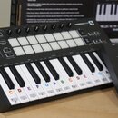 Černý MIDI kontrolér s klávesnicí a mřížkou bílých padů. Na horním panelu je nápis LAUNCHKEY a řada tlačítek s označením Pitch, Modulation, Arp, Temp…