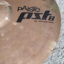 Detailní pohled na mosazný činel s viditelným broušením. Na povrchu je černý nápis pAiste pst 8 a pod ním text 20" MEDIUM RIDE. Povrch vykazuje drobn…