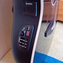 Detailní pohled na boční část akustické kytary s černým plastovým korpusem a bílým lemováním. Na kytáře je umístěn ovládací panel s nápisy TREBLE, BA…