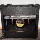 Zadní strana černého kytarového komba s texturovaným povrchem. Na horním panelu jsou dvě nálepky, z nichž jedna nese nápisy VINTAGER AC108 15 WATT VA…