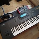 Černý digitální klavír značky YAMAHA s modelem QS30. Nástroj má bílé a černé klávesy, displej a řadu ovládacích tlačítek. Vedle klavíru leží černá sl…