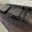 Detail elektrické kytary s černým trpytivým povrchem a černým pickguardem. Nástroj má dva černé humbuckery s nápisem EMG a dvě černé ovládací knoflík…