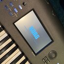 Detailní pohled na ovládací panel černého klávesového nástroje. Na displeji je zobrazen modrý nápis KORG a pod ním se nachází označení TouchView. V h…