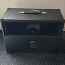 Černý kytarový reproduktor v bedně potažené texturou imitující kůži s kovovými rohy a úchytem. Uprostřed spodního panelu je nápis Mesa/Boogie v dopro…