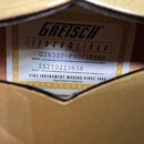 Detailní záběr na bílý štítek s černým textem, který je vlepen do dutiny hudebního nástroje. Na štítku je nápis Gretsch, pod ním v rámečku STREAMLINE…