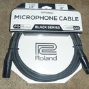 Černý mikrofonní kabel v originálním papírovém obalu. Na obalu jsou nápisy MICROPHONE CABLE, BLACK SERIES, LOW CAPACITANCE a LIFETIME GUARANTEE, dále…