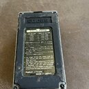 Fotografie zachycuje zadní stranu šedého efekt pedálu značky BOSS. Na přístroji je nalepený štítek s nápisy BOSS AC ADAPTOR, tabulkou napájecích adap…