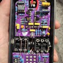 Fotografie zachycuje vnitřek efekt pedálu v černém plastovém šasi. Uvnitř jsou dvě fialové DPS s elektronickými součástkami, जिनमें jsou vidět nápisy…