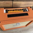 Kytarové kombo v oranžovém texturovaném potahu s černými plastovými rohy. Na horním ovládacím panelu je nápis ORANGE a štítek s textem ROCKERVERB 50…