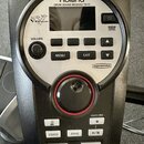 Černý elektronický bubenový modul značky Roland s označením DRUM SOUND MODULE TD-11. Na předním panelu je stříbrný ovál s nápisy V-Drums a SuperNATUR…