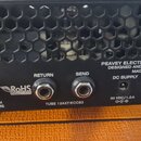 Zadní strana černého kytarového zesilovače s kovovou mřížkou. Na šasi jsou nápisy PEAVEY ELECTRONICS CORPORATION, DESIGNED AND ENGINEERED IN U.S.A.,…