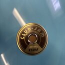 Detailní pohled na světle modrý povrch bubnu s kovovým logem. Na kulatém zlatavém štítku je nápis CLUB-JAM, MADE IN CHINA a TAMA. Uprostřed štítku je…