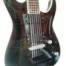 Elektrická kytara s tmavým, pravděpodobně černým lakovaným povrchem s viditnou strukturou dřeva. Nástroj má dva humbuckery, dva ovladače a stříbrný m…