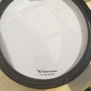 Fotografie znázorňuje elektronický bicí pad bílé barvy s černým obručováním. Na povrchu jsou nápisy „Roland“, „V-Drums“ a text „Registered in U.S. Pa…
