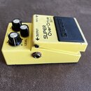 Žlutý efekt pedál s černým gumovým spínacím tlačítkem. Na horní části jsou nápisy INPUT, OUTPUT, SUPER OverDrive SD-1 a na tlačítku značka BOSS. Pedá…