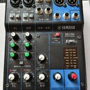 Modrý a černý mixovací pult Yamaha MG06. Na zařízení jsou viditelné nápisy YAMAHA, MG06 MIXING CONSOLE a různé označení vstupů a ovládacích prvků jak…