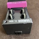 Kytarový efekt pedál v černé barvě s fialovým stupněm. Na horní části je nápis FLANGER a v dolní části bílý text YAMAHA FL-10M. Zařízení má čtyři čer…