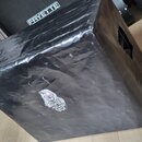 Černý krycí plášť z plastového materiálu přes hudební zařízení. Na plášti je nalepená bílá nálepka s obrázkem lebky a nápisem "KAPPA COFFEE" a logem…