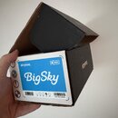 Kartonová krabice s černým povrchem a bílým štítkem. Na štítku je modrý obdélník s bílým nápisem BigSky a nad ním značka strymon oraz symbol MIDI. V…