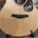 Detailní pohled na korpus akustické kytary světlé dřevěné barvy. Nástroj má tmavý hmatník, černý kobylník a hnědo-oranžový pickguard s mramorovým vzo…
