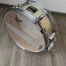 Kytarový basový buben se stříbrným kovem a zlatavým třpytivým povrchem korpusu. Na přední bláně je černé logo GREISCH a malý oválný nápis EVANS. Horn…