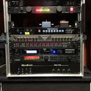 Stříbrný rackový kufřík s několika zařízeními. Obsahuje jednotky s nápisy KORG, The Rocket VM-100, ROCKTRON TriAxis, ROCKTRON HUSH a Mesa/Boogie Fift…