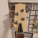 Fotografie zachycuje hlavu basové kytary v krémové barvě. Na horní části je nápis Jantar bass. Nástroj má čtyři kovové ladičky, z nichž jsou vidět tř…