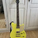 Žlutá elektrická kytara s tmavým hmatníkem a černou hlavou. Na hlavě je viditelné logo Yamaha. Tělo má dva snímače typu humbucker, jeden tónový a jed…