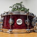 Bordeaux červený snare drum s chromovaným obručováním a mechanismem na napnutí koženého membrány. Na korpusu je bílý kulatý štítek s nápisem drums dw…