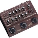 Hnědý kytarový předzesilovač s nápisy BOSS a Acoustic Preamp AD-10. Zařízení obsahuje řadu ovládacích knoflíků, přepínačů a červeně svítící digitální…