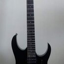 Černá elektrická kytara s černým hmatníkem a černým hardwarem. Na hlavě je bílý nápis Ibanez. Kytara má dva humbuckery, tremo lo systém a dvě ovládac…