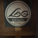 Fotografie detailu štítku uvnitř akustického nástroje. Štítek je kulatý, černo-bílé provedení s nápisy ROCK CHIC GUITARS, velkým logem LAG, názvem mo…