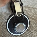 Černá nadušnice s bílými prvky a nápisem AKG na horní části náušniku. Na vnější straně sluchátka je nápis Reference Headphones K702. Povrch plastů vy…