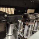 Detailní pohled do vnitřku elektronického zařízení s řadou elektronických vakuových elektronek. Na černém komponentu vlevo je bílý nápis MESA 562802…