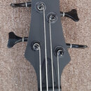 Černá hlava basové kytary s nápisy SDGR a SOUNDGEAR BY IBANEZ. Nástroj má čtyři ladicí kolíky s černými knoflíky a čtyři kovové struny. Povrch hlavy…