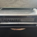 Černý kytarový zesilovač Ampeg SVT-3 PRO umístěný v transportním flightcasu s hliníkovými hranami. Na předním panelu jsou ovládací knoflíky a posuvní…