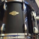 Černý buben s chromovaným obručováním a hardwarem. Na korpusu je oválný zlatý štítek s nápisy Pearl, Masters a PREMIUM MAPLE. Na horním a dolním obru…