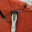 Stříbrný sustain pedál značky Roland s černým logem. Pedál má kovové tělo a žebrovaný povrch horní části. Z přístroje vedou dva černé kabely, z nichž…
