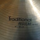 Detailní záběr na povrch kovového činele s viditelným koncentrickým drážkováním. Na povrchu je černý nápis Traditional REGULAR HI-HAT a níže údaj 14"…