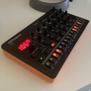 Černý kompaktní sekvencér s oranžovým spodním panelem. Na zařízení je bílý nápis Roland a model T-8, červený digitální displej zobrazuje hodnotu 106.…